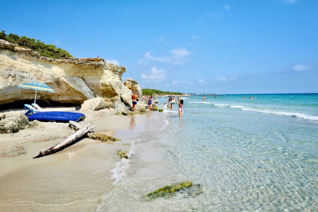 Beachgoers wandering the sand of Baia dei Turchi in the Puglia region of Italy.