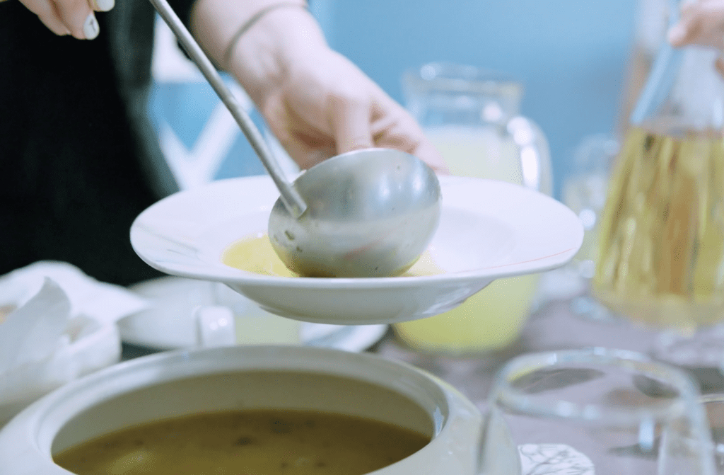 Homemade soup is ladeled into a white bowl
