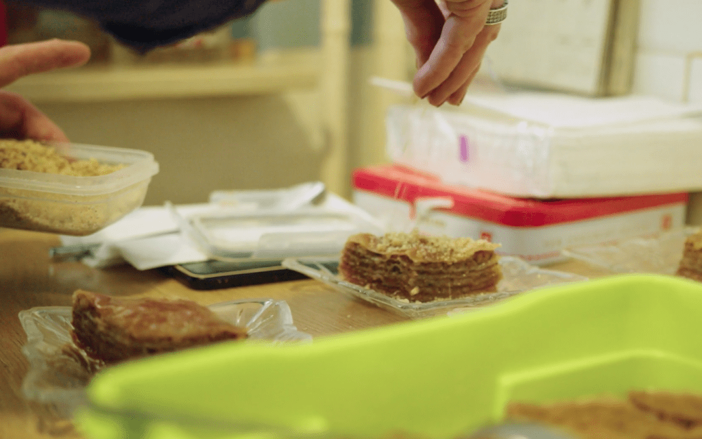 A hand dusts pistachios over homemade baklava in Sarajevo, Bosnia