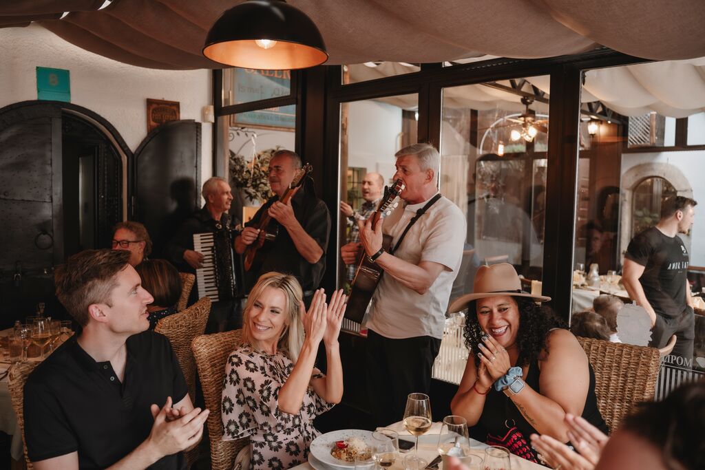 Group of Trafalgar guests applauding a live music performance at a restaurant