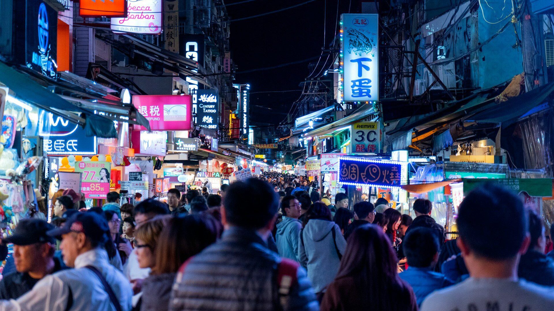 Photo of a busy shopping street in Taipei, Taiwan. Neon signs line each side of the streets, while people crowd the pedestrianised zone