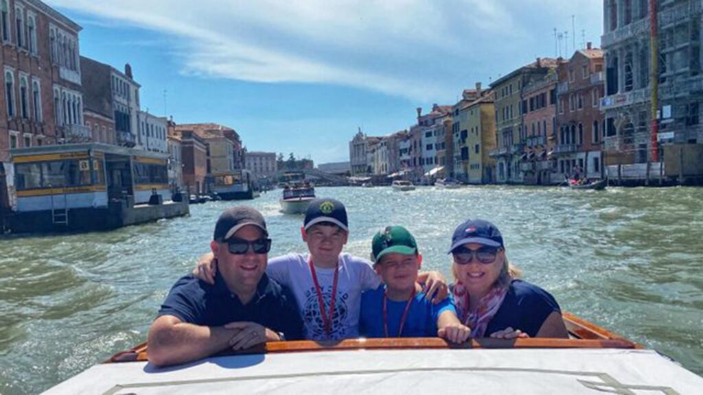 Photo of Megan with her husband and two sons on a boat on a canal in Venice