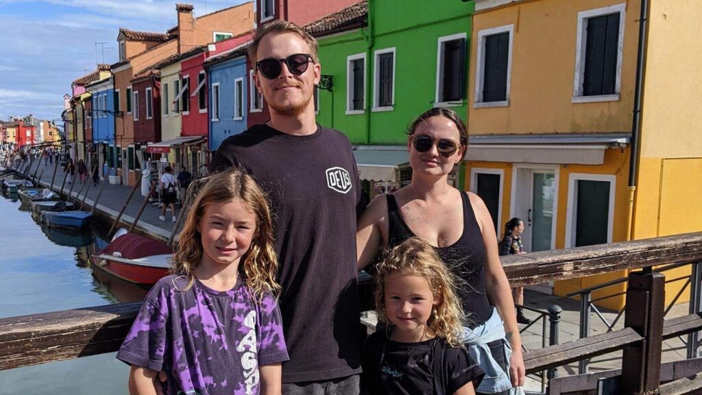 Georgia and her husband and two kids photographed in front of the colorful houses on the island of Burano