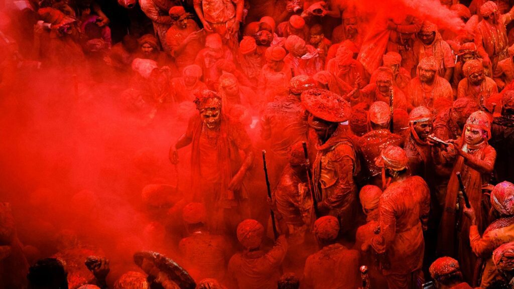 A crowd of people covered in red powder at Holi