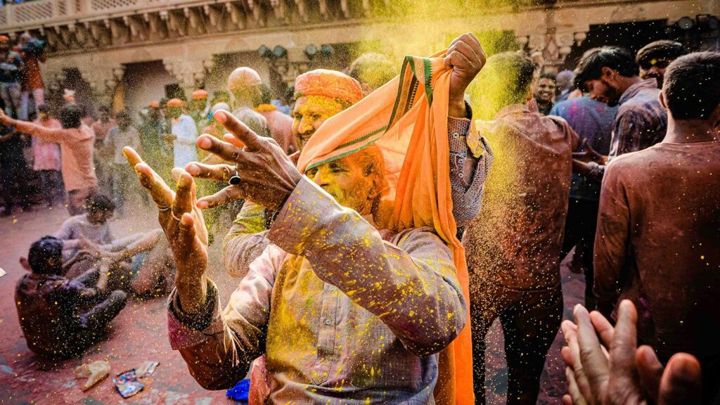 Two men celebrate Holi by throwing colored powder