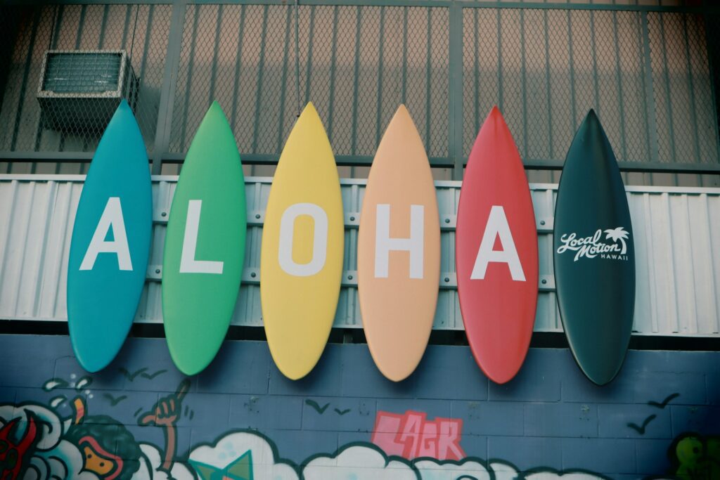 Surf boards lined up, each with a letter on spelling out 'Aloha'