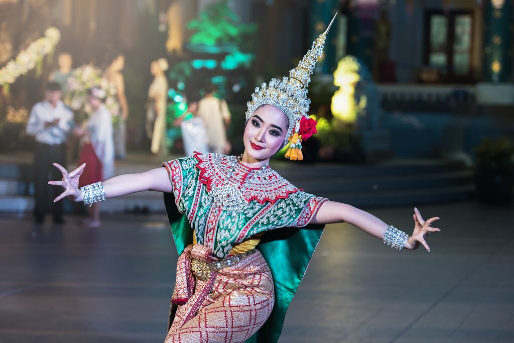 A woman dances in traditional Thai dress, adorned with green, red and yellow colours.