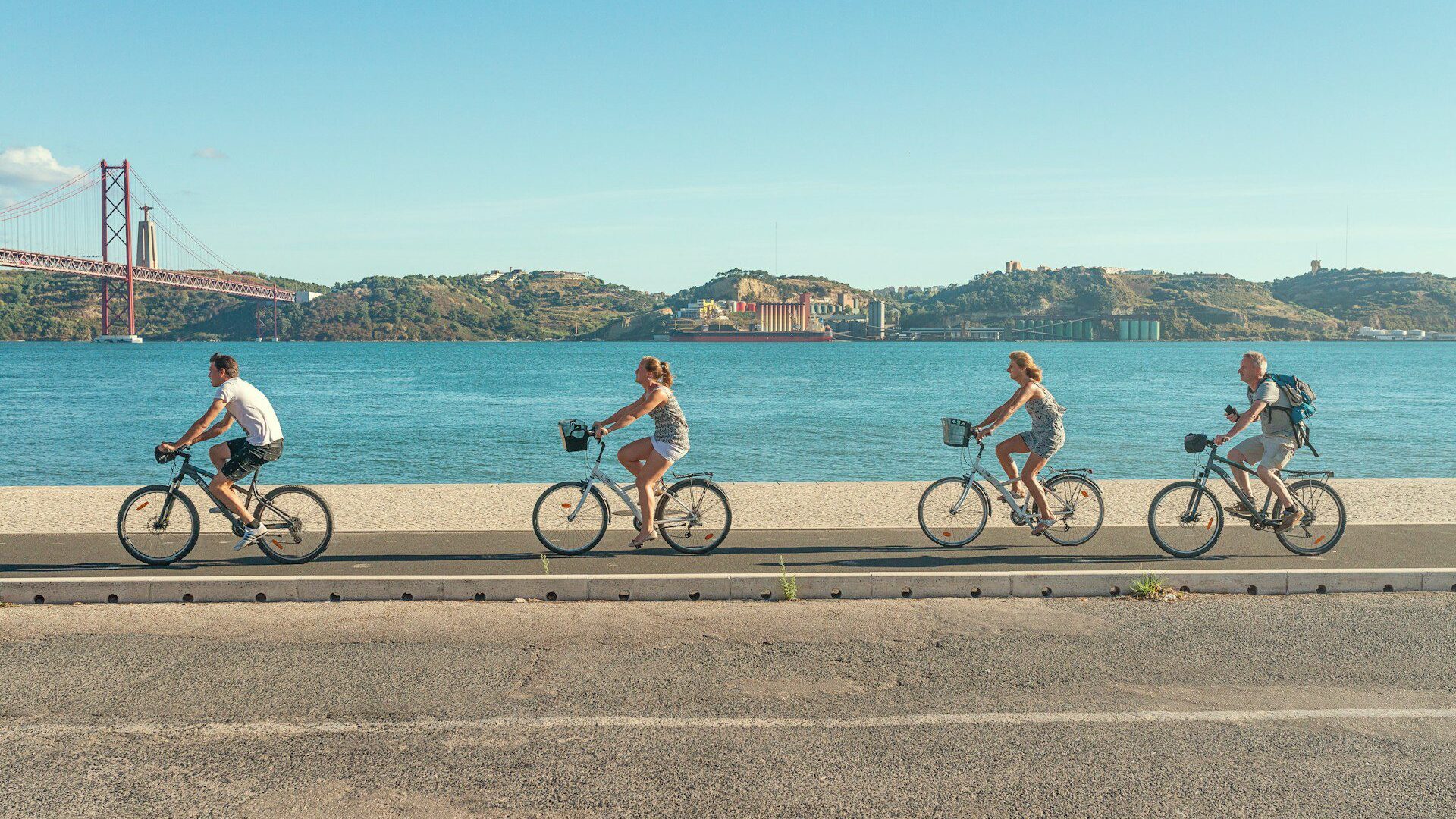 Family riding a bike along the riverside in Lisbon