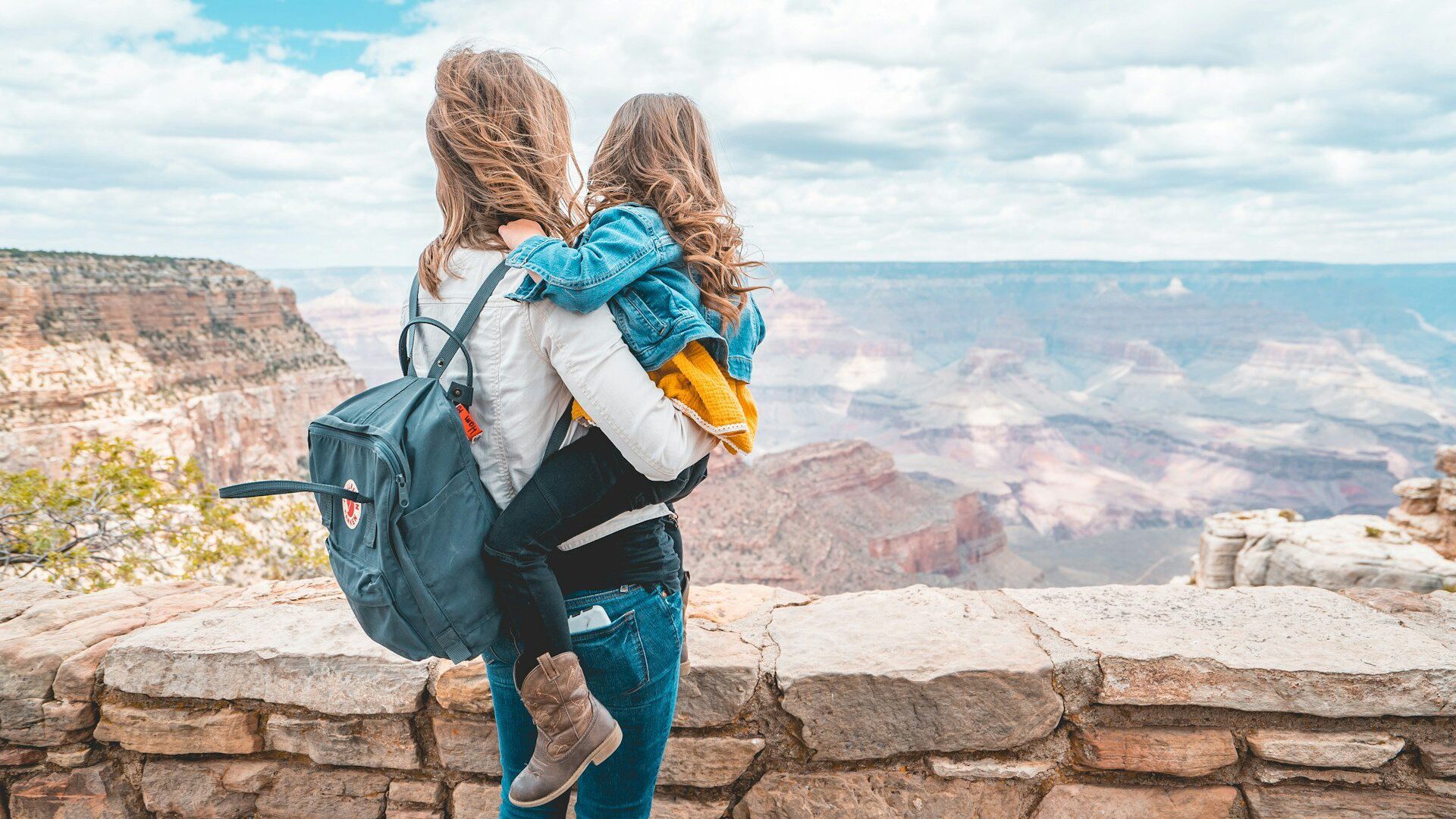 A mother holding her young child looking out over the Grand Canyon