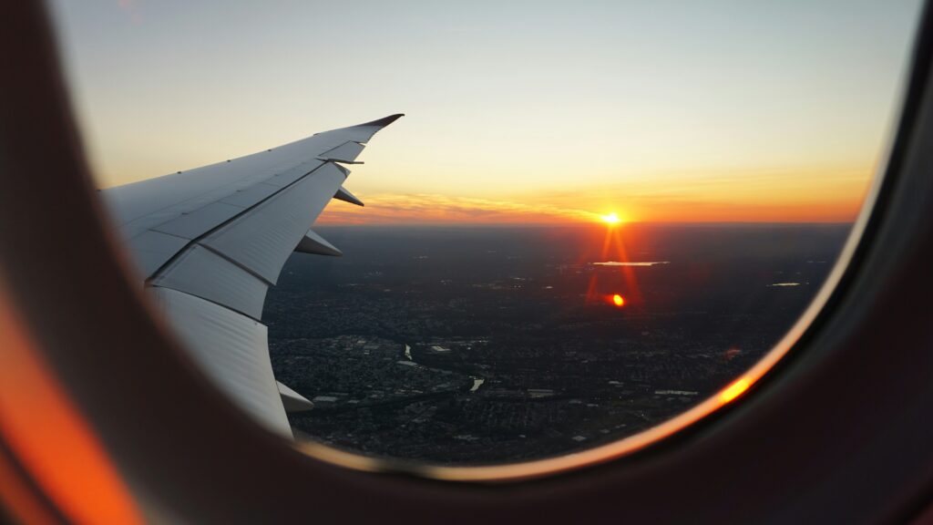 Sunset can be seen from the windows of a plane, overlooking the wing