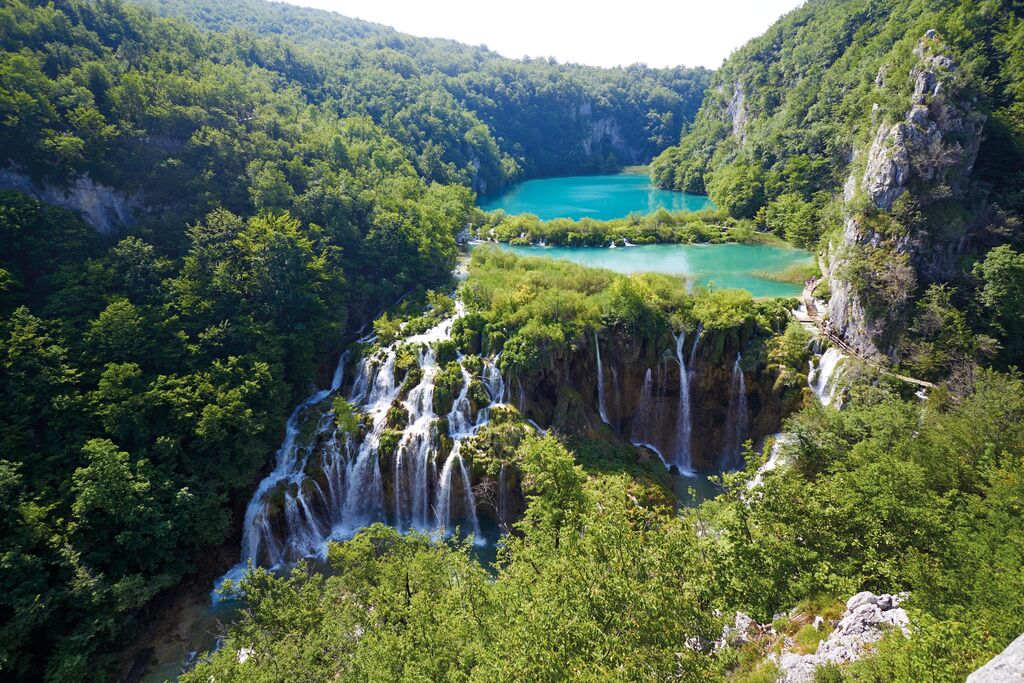 Plitvice National Park: cascading waterfalls, emerald water and lush vegetation fill a beautiful valley.