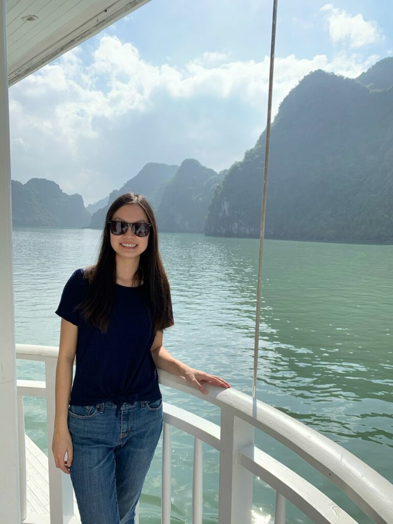A woman with sunglasses poses for a photo with Vietnam's islets in the background