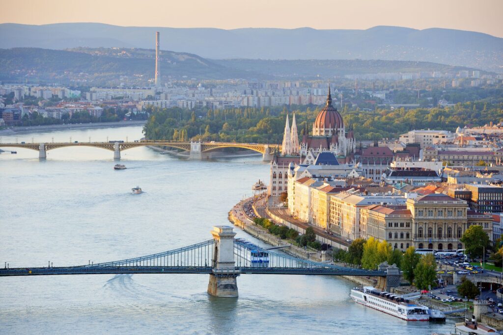 Large birds-eye-view of budapest and its river, bridges, and hills in the horizon.