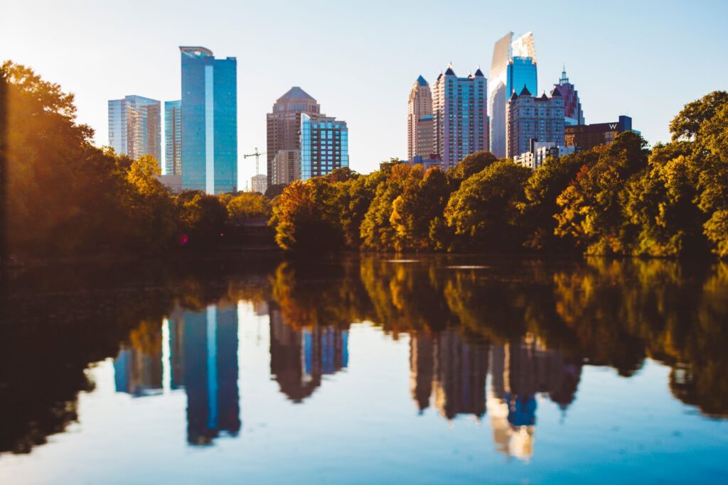 A lake in Atlanta, Georgia with shrubbery and tall city buildings in the back