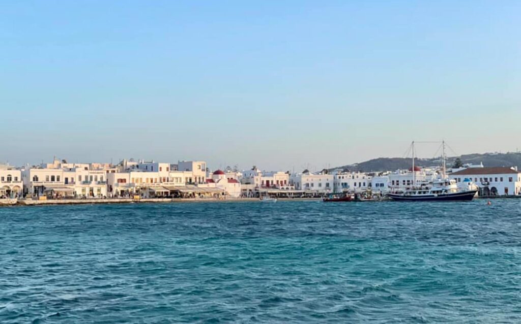 White, bleached houses sit looking out at a deep blue ocean in Greece