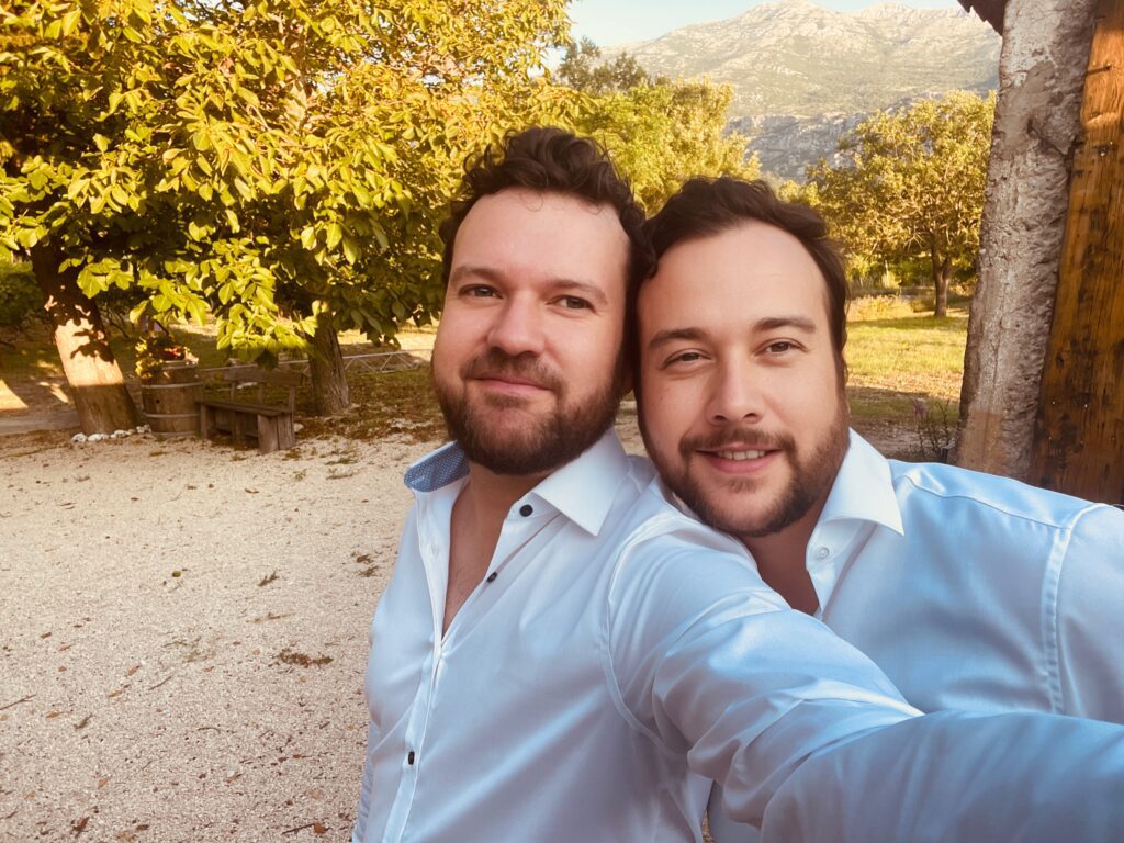Craig and Graham posing for a photo in white hsirts at a beautiful vineyard