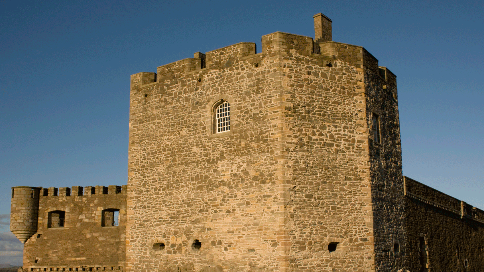 A stone castle with a grassy field in the background.