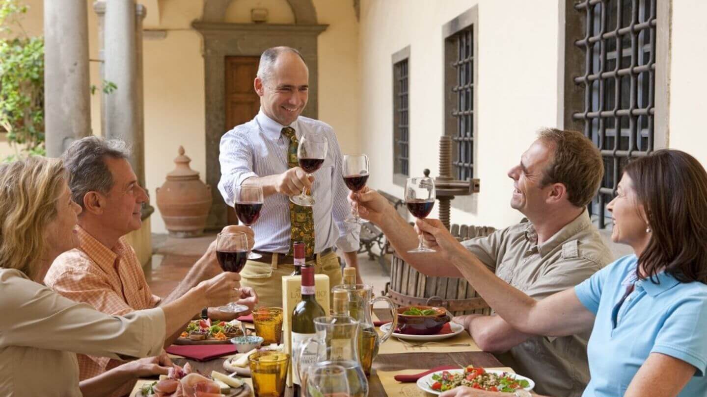 A group of people enjoying wine at an outdoor table during their travels.