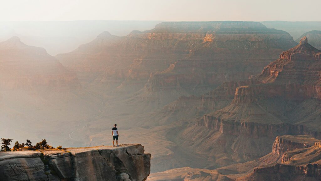 A man standing on the edge of the Grand Canyon looking out