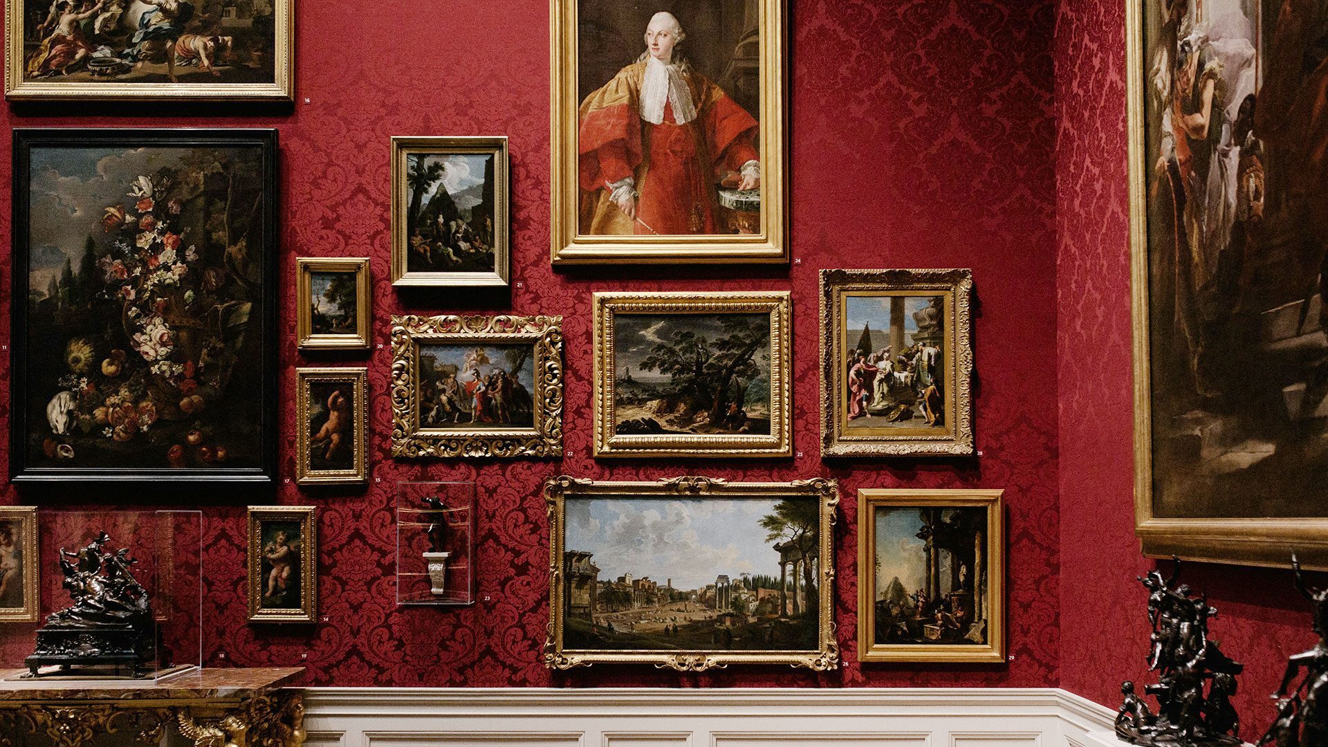 A room with red wallpaper filled with paintings