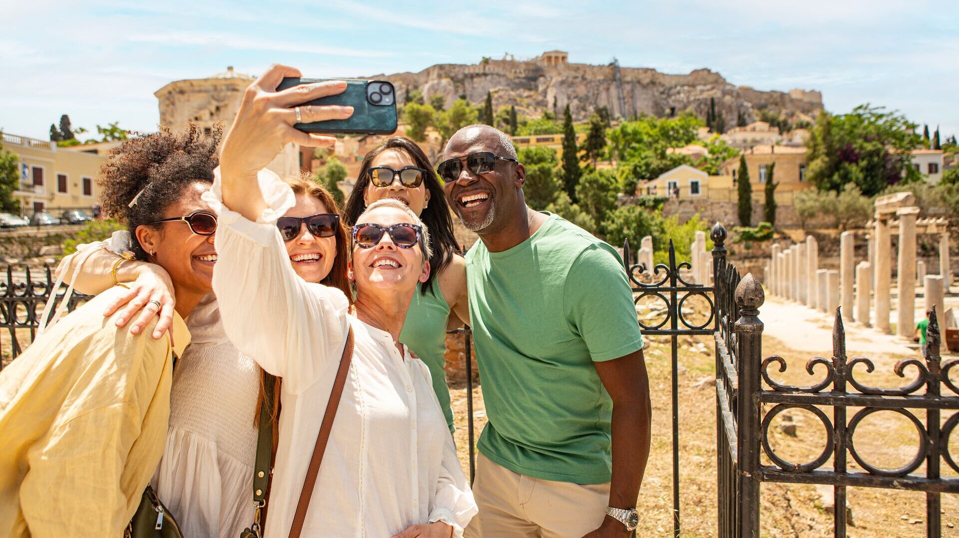 Group of mature travelers posing for a group selfie in front of the Acropolis, Greece