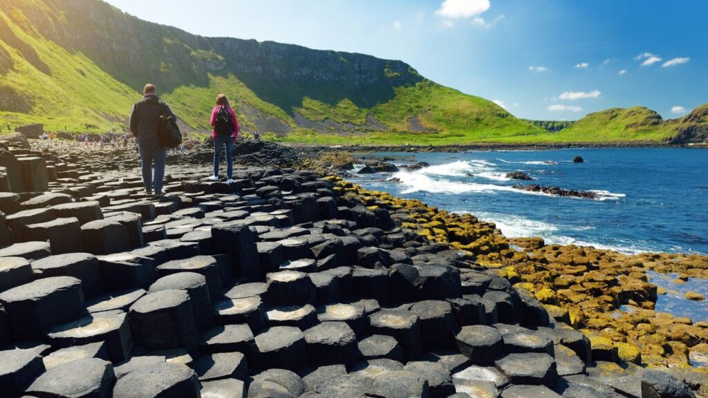 A couple walking along the hexagonal basalt columns of the Giant's Causeway in County Antrim, Northern Ireland.