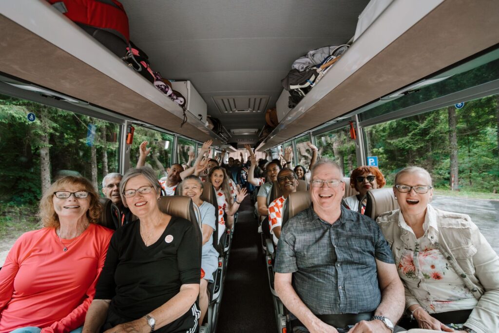 A group of guests smiling towards the coach driver as he takes them around on his coach