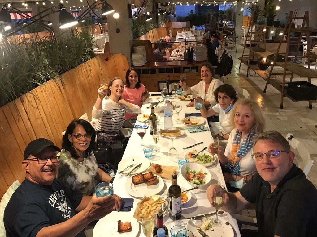 New travel friends on their group tour Welcome dinner, smiling and raising glasses