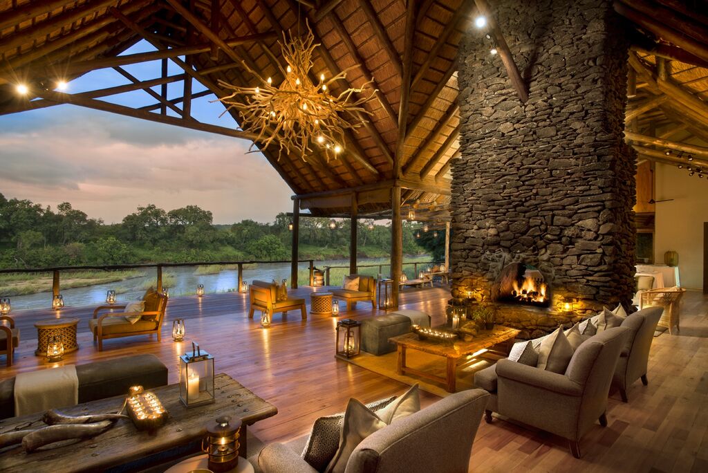 Interior of a luxury safari hotel with open front overlooking green landscape