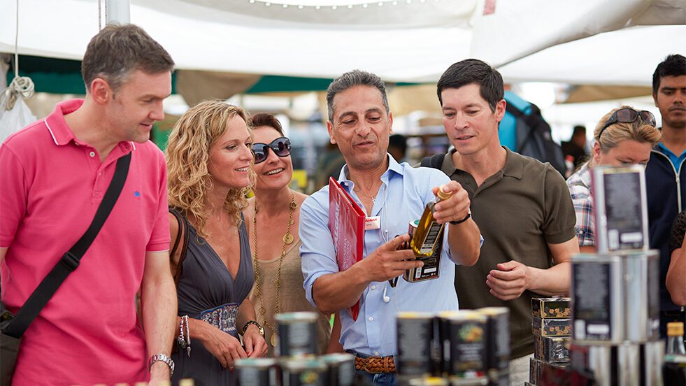 Man showing tourists a bottle of olive oil