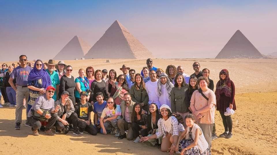 people on tour in egypt, pyramids in background