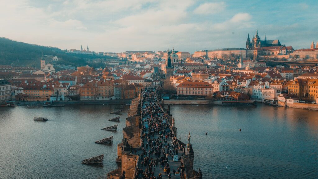 Aerial view of Charles Bridge crowded with people, with Prague Castle in the background at dusk during European trips.