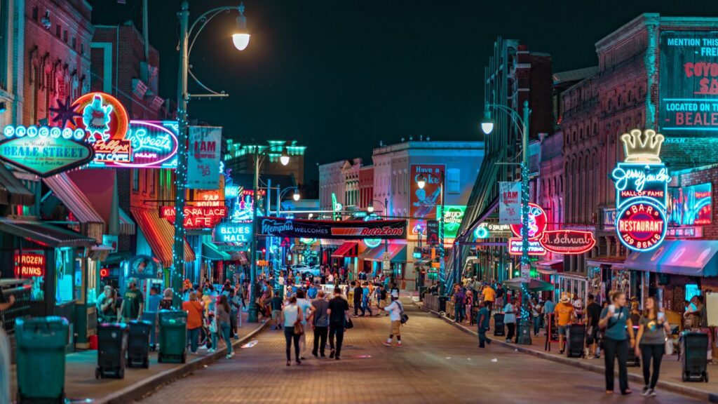 Vibrant nightlife scene with neon signs and pedestrians on Beale Street, perfect for those looking for female travel tips.