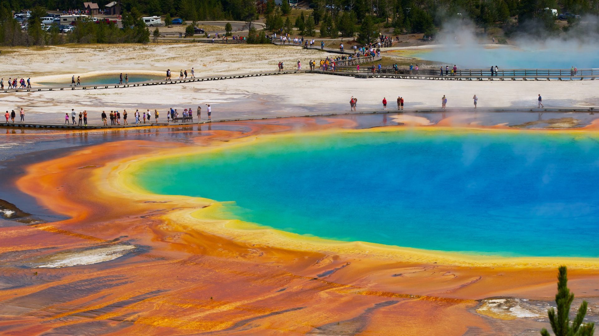 Visitors walking along boardwalks around the vibrant, multicolored Grand Prismatic Spring in Yellowstone, the largest national park in the US.