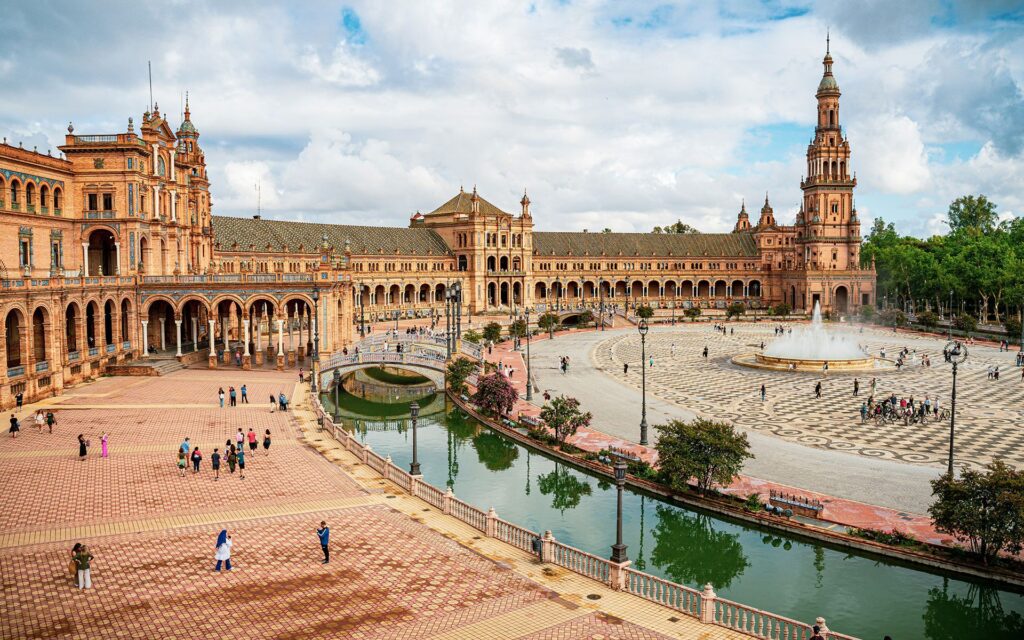 Large historic Plaza de España in a European city with a large fountain in the centre.