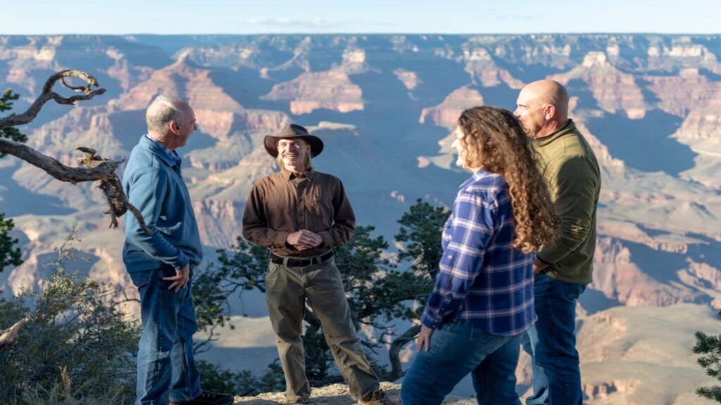 Experience the breathtaking grandeur of the Grand Canyon with four people standing on a cliff, a must-see attraction when visiting the USA.