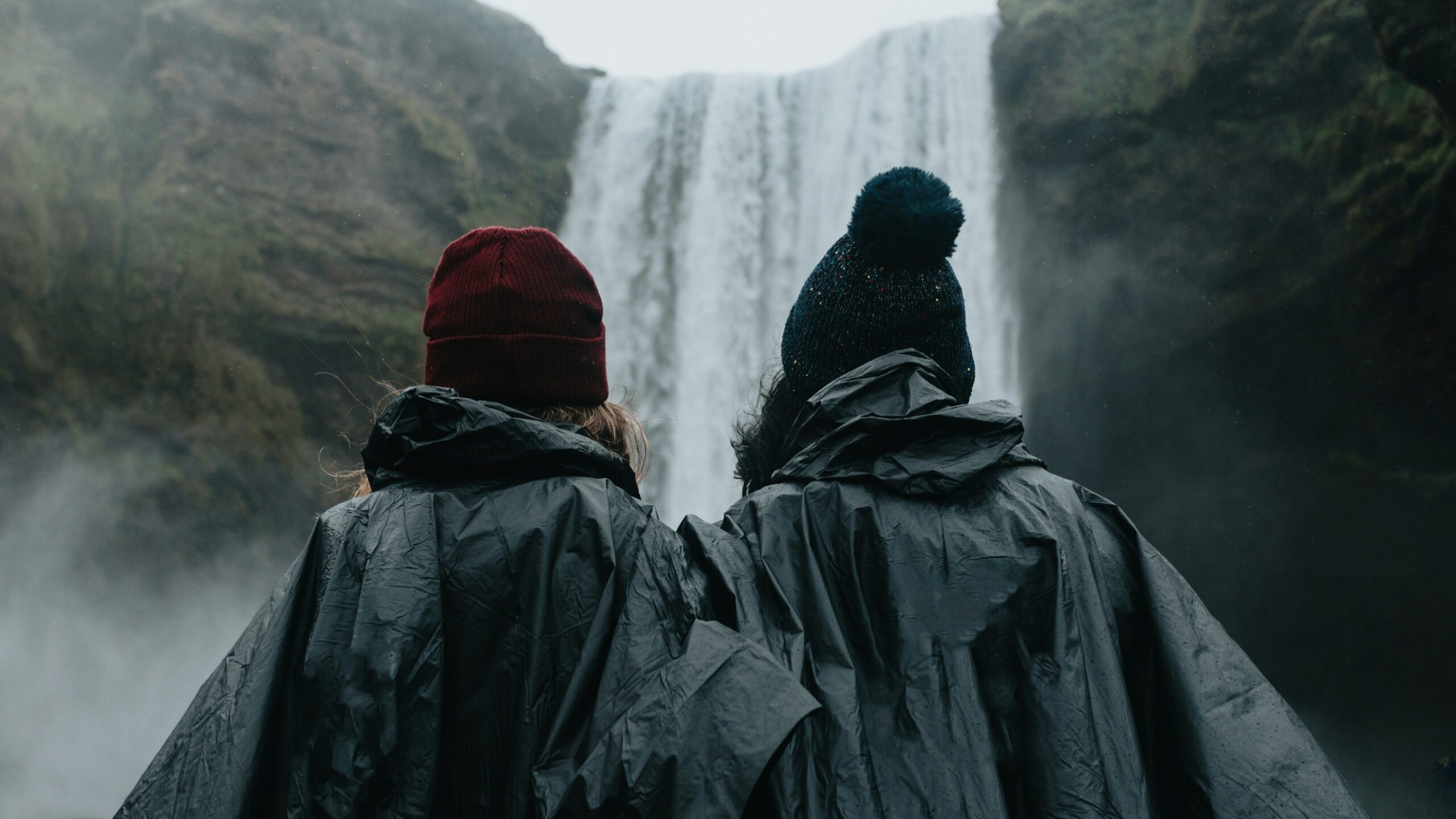 two people in raincoats at a waterfall
