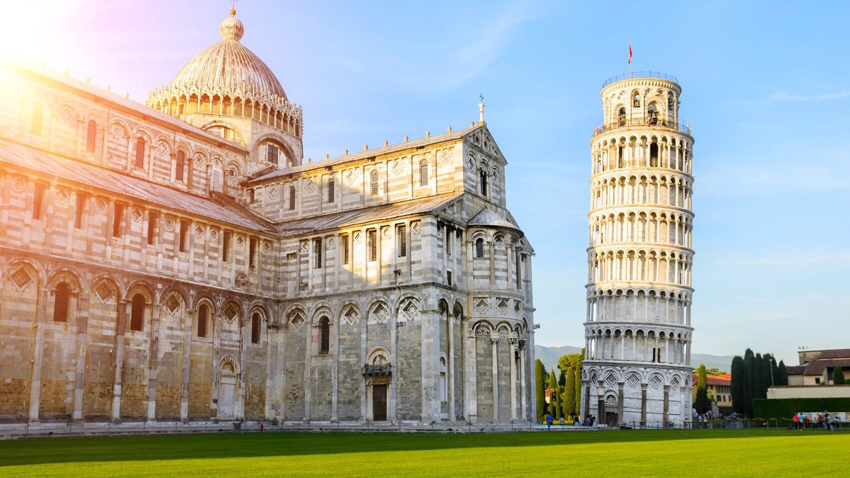 Leaning Tower of Pisa, Italy, with a green lawn in front of it. Clear, blue skies and sunny.