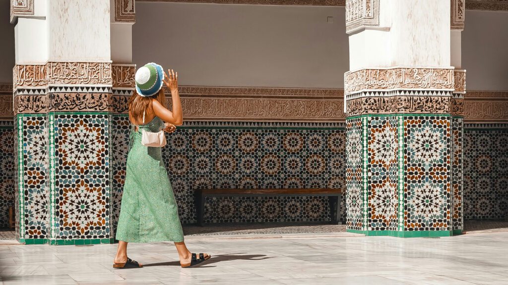 Woman walking past building with brightly coloured decorative tiles in Morocco