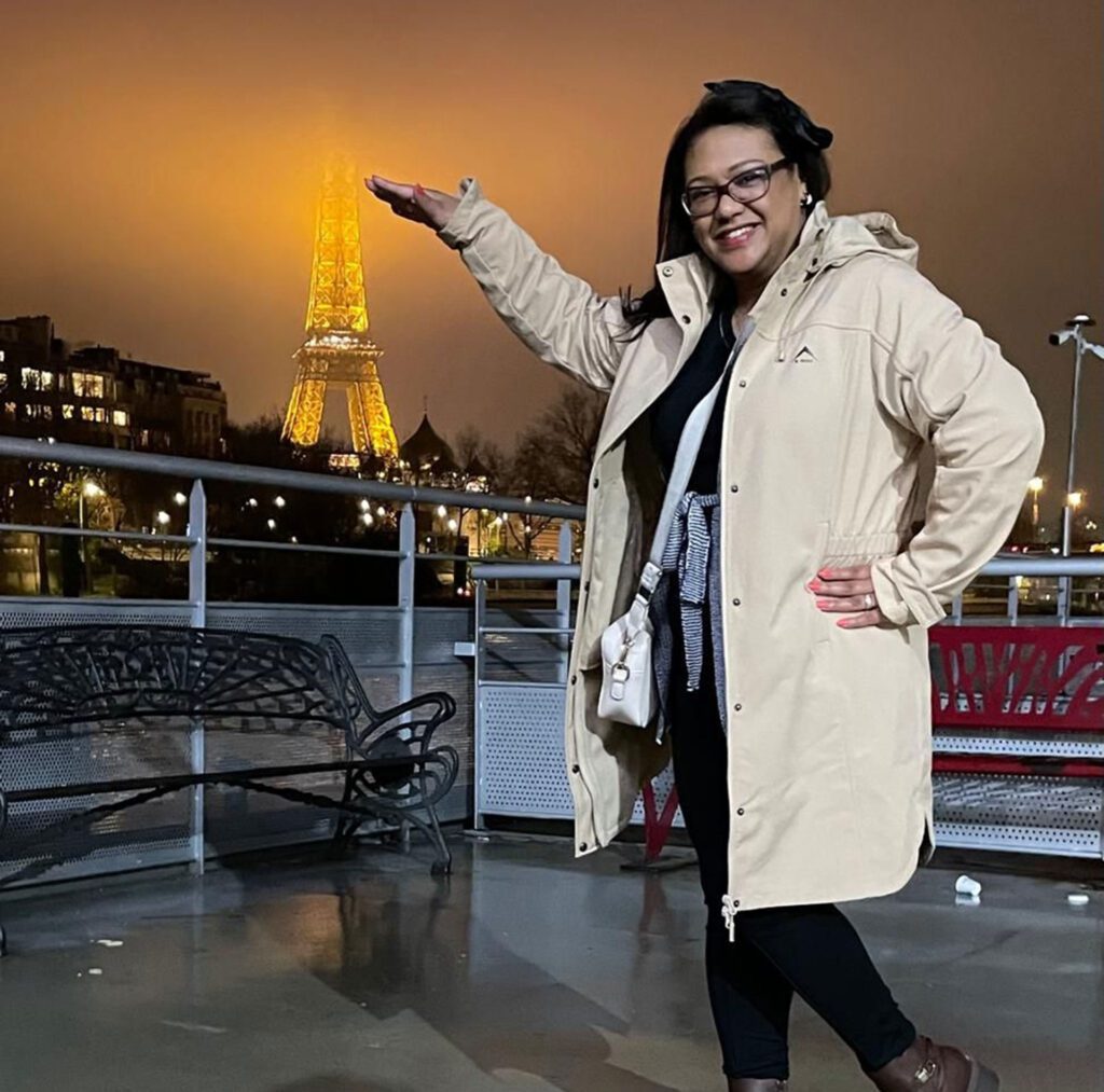 Past guest Chantel posing in front of the Eiffel Tower lit up at night
