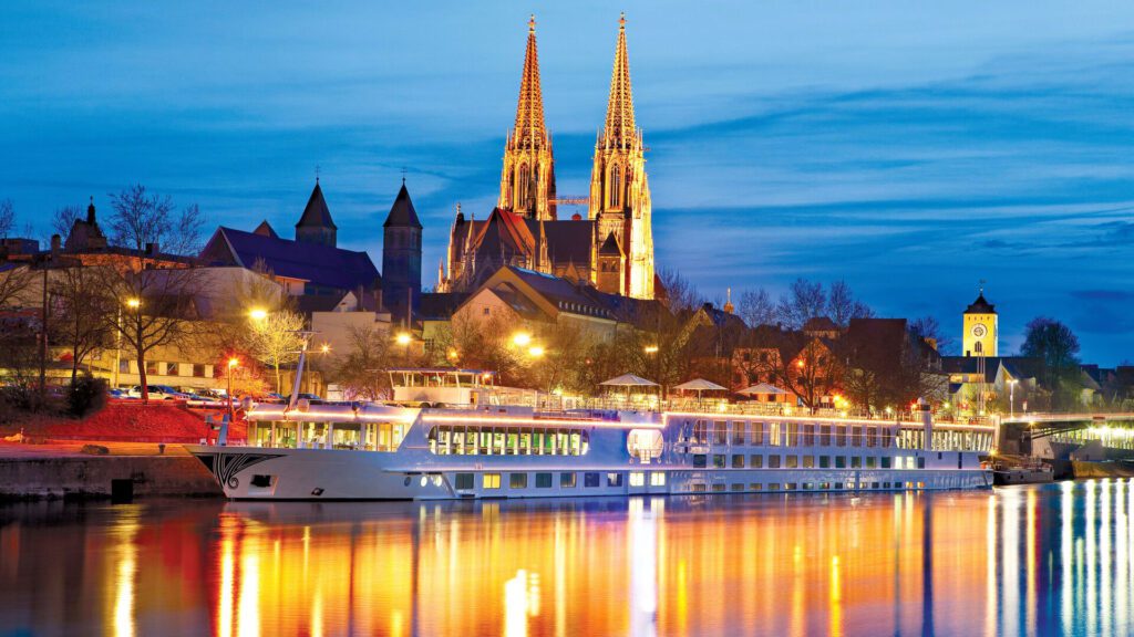 River cruise boat in front of a church on the Danube at nighttime