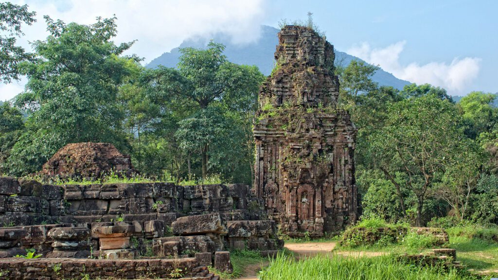 Ancient temple ruins surrounded by woodland with mountain in the background