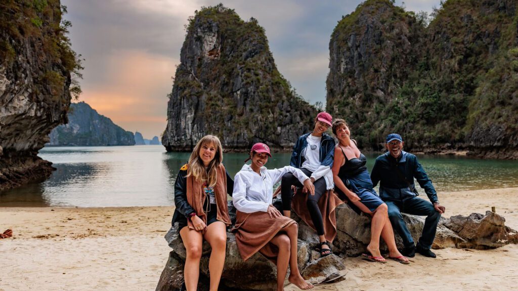 Group of trafalgar travelers sitting on a rock with Ha Long Bay in the background