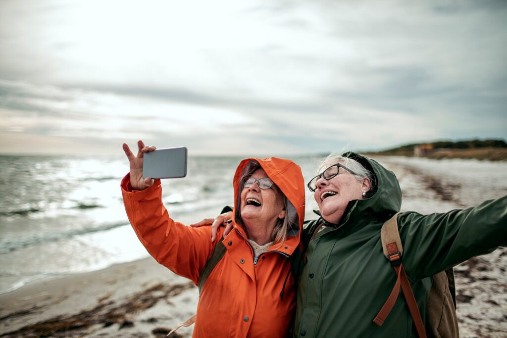 Two mature women taking a photo on a beach 