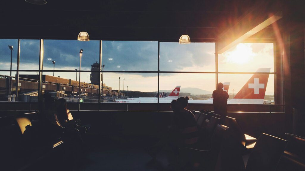 Sun shining through the window at an airport, silhouetting person looking out
