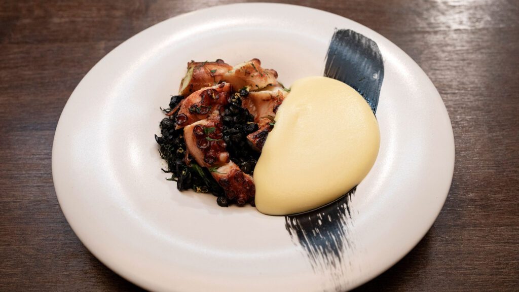 A dish of charred octopus with squid ink lentils