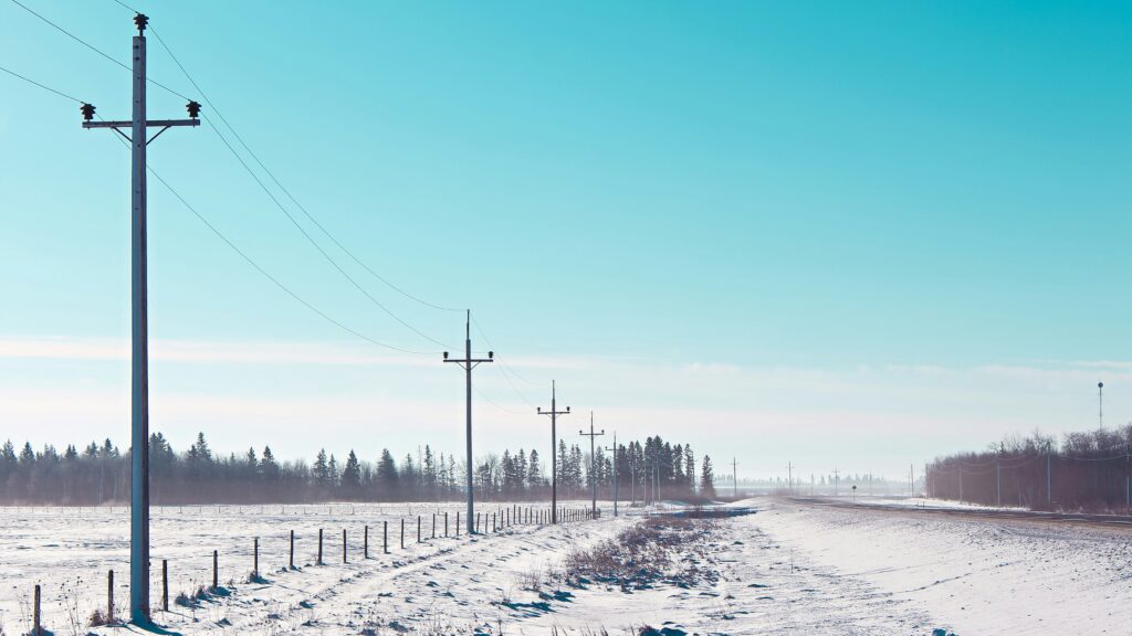 Telephone poles follow a road through a snowy landscape in Manitoba