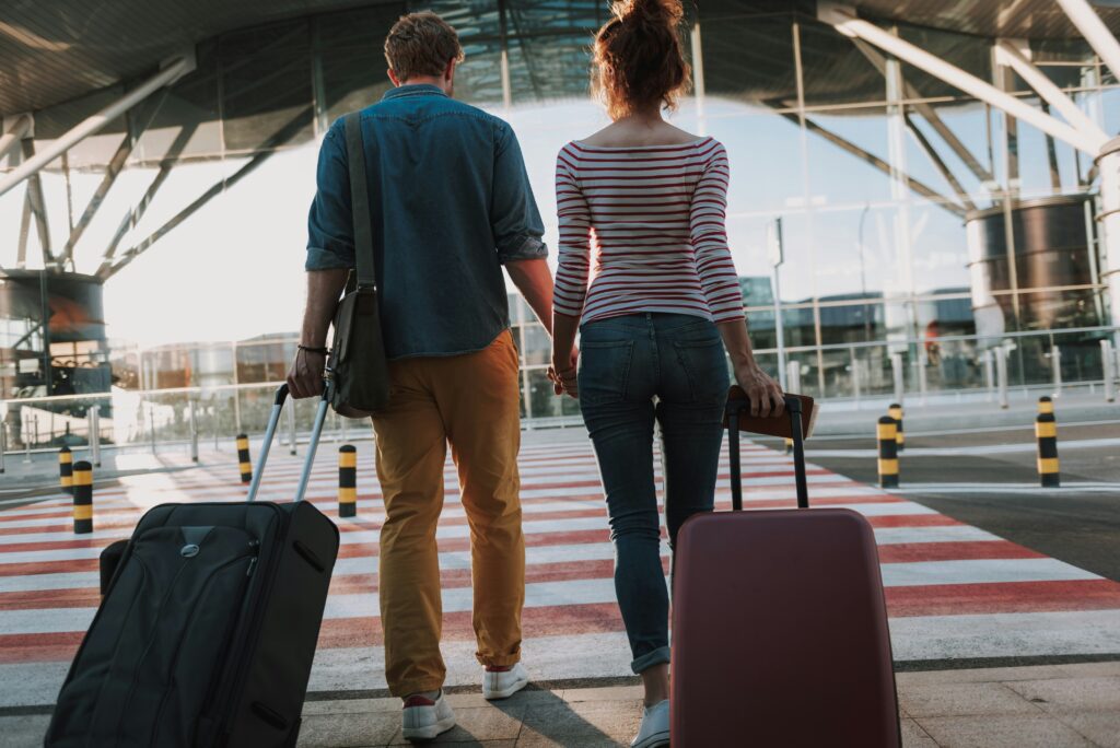 couple walking into airport with suitcases