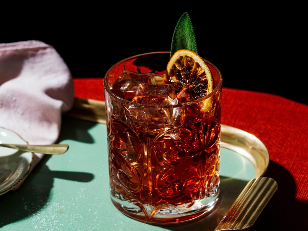 A negroni with orange garnish on a serving tray