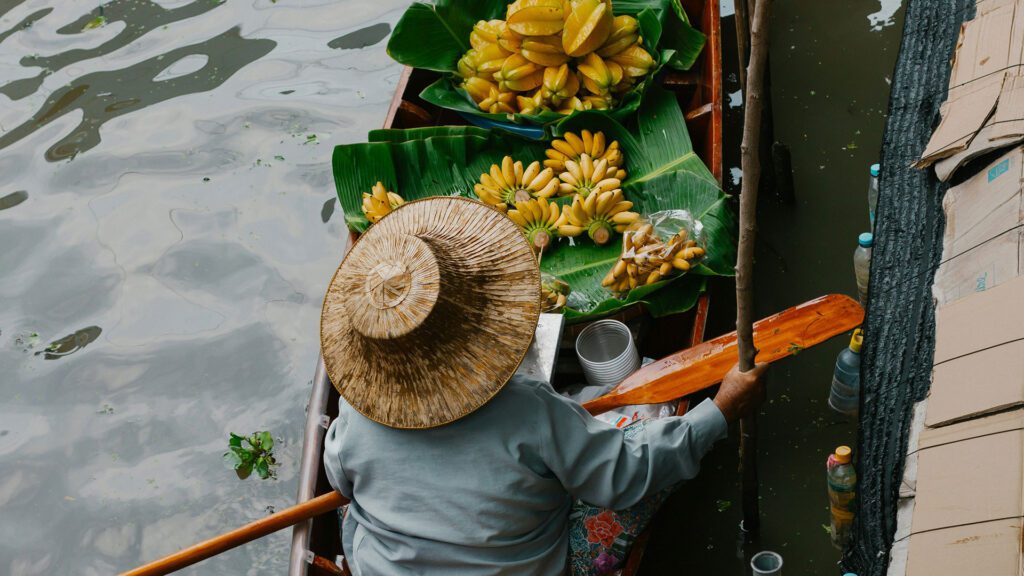 Vietnamese man paddling a traditions canoe filled with fruit